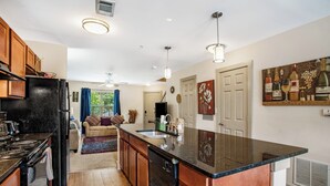 A modern kitchen with a central island, wooden cabinets, and a black countertop. - New Spacious Home in the Heart of Downtown Atlanta (Atlanta)