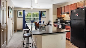 A modern kitchen with a central island, wooden cabinets, and a black refrigerator. - New Spacious Home in the Heart of Downtown Atlanta (Atlanta)