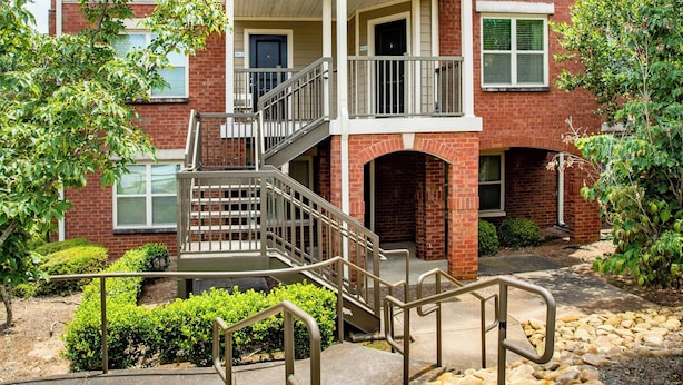 A multi-story brick building with a central staircase, a covered porch, and a landscaped garden with rocks and shrubs. - New Spacious Home in the Heart of Downtown Atlanta (Atlanta)