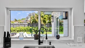 A modern kitchen with a large window, a sink, and a potted plant.