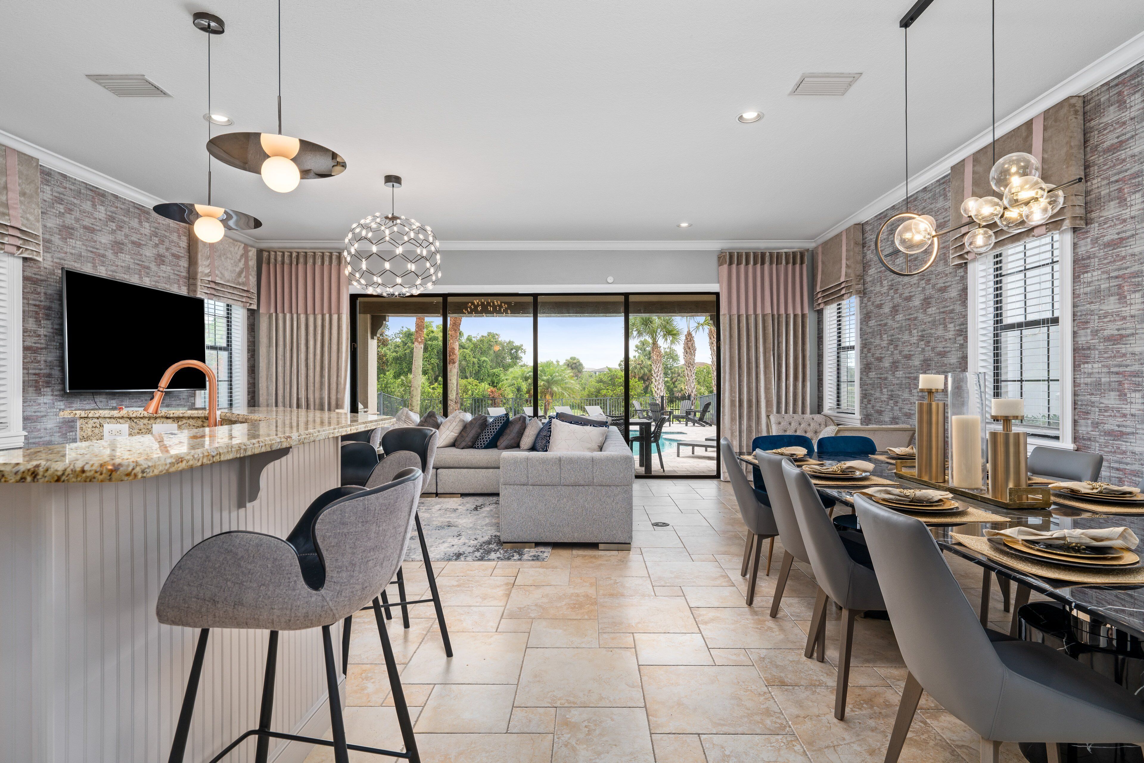 A modern kitchen with a large island, bar stools, and a dining area with a table set for six.