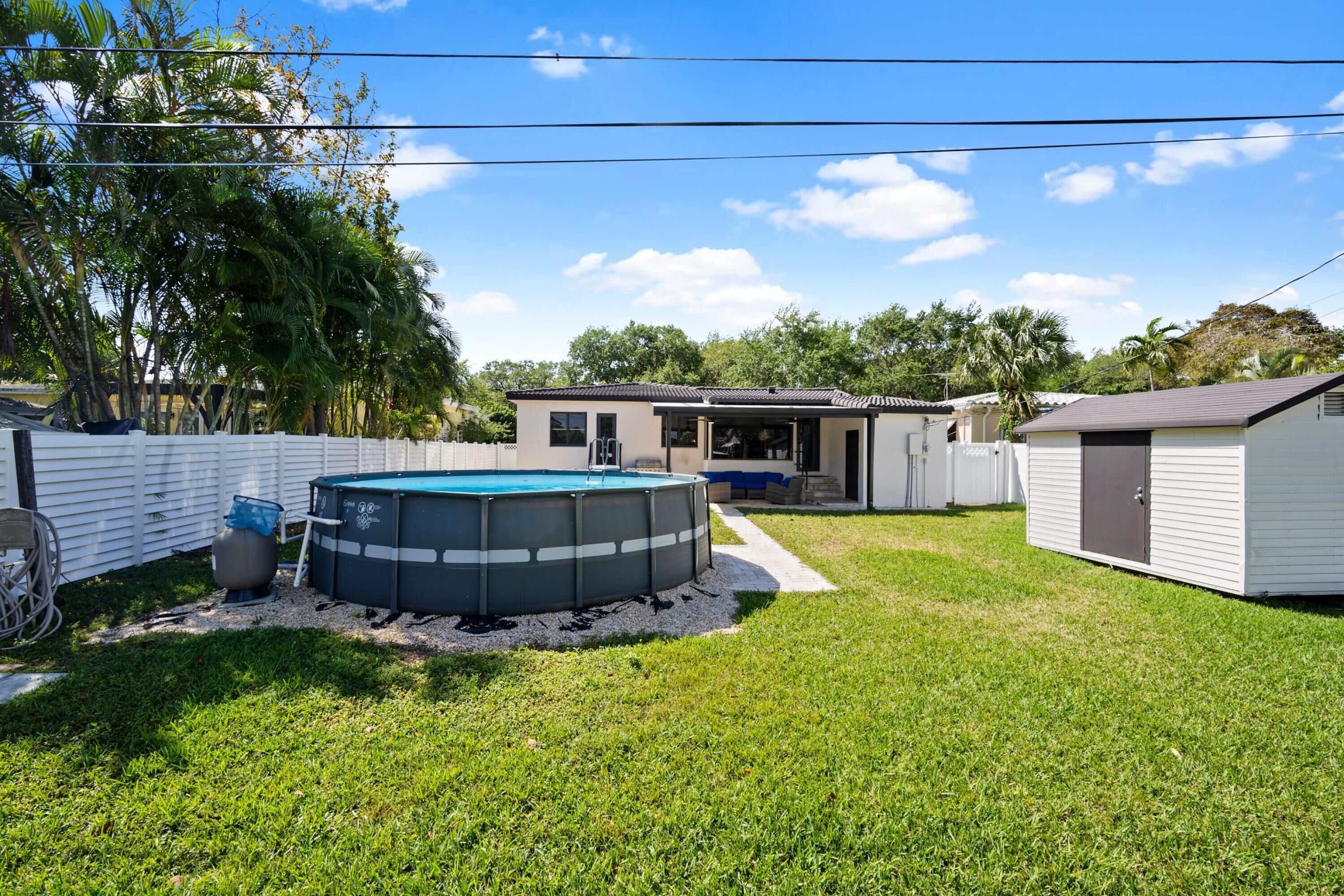 Ein Garten mit Swimmingpool, Gartenhaus und einem Haus.