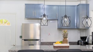 A kitchen with blue cabinets, a stainless steel refrigerator, and a fruit basket on the counter. - Caldera Villas (Soufrière)