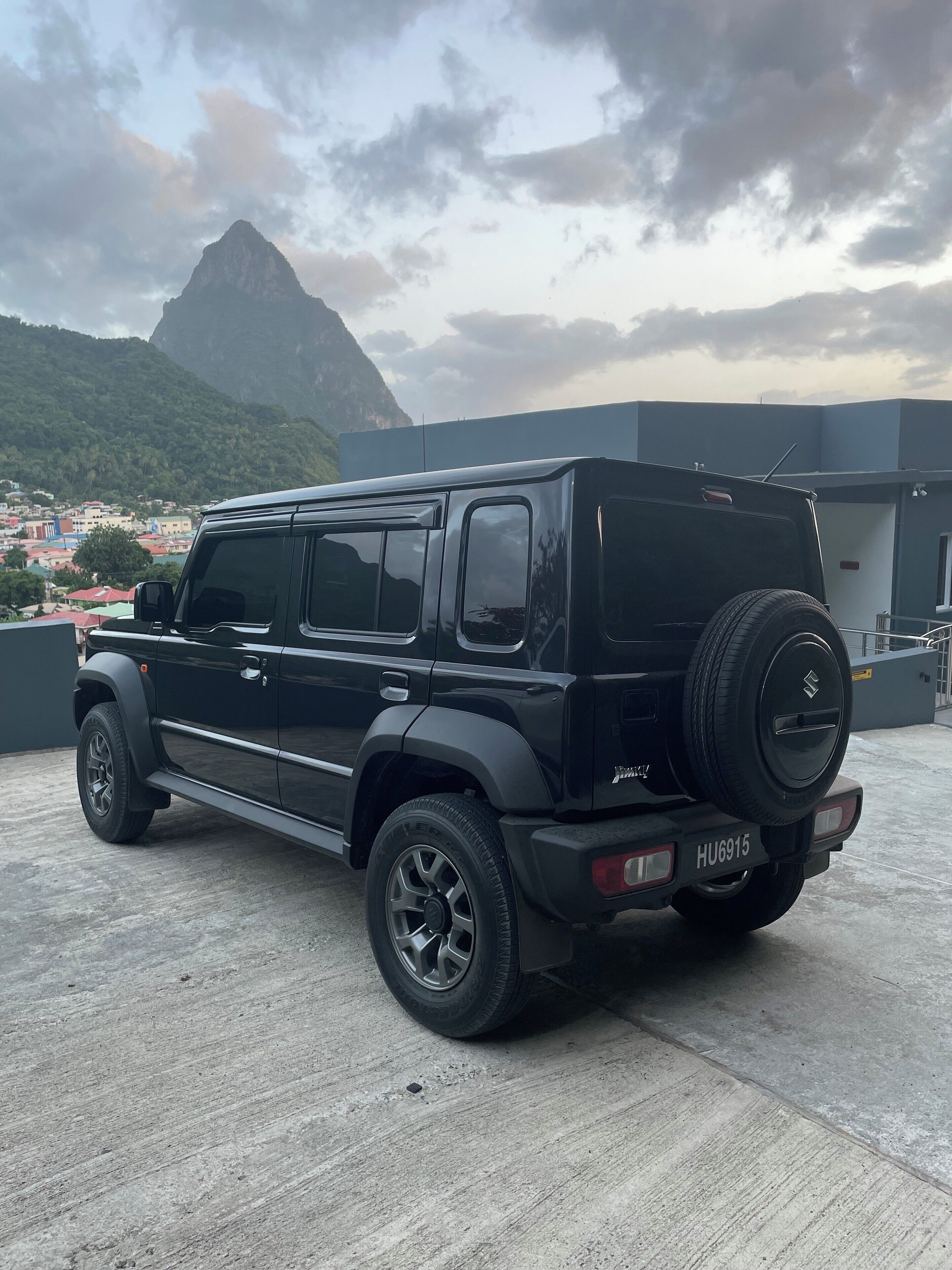 A black SUV parked on a rooftop with a cityscape and mountains in the background.