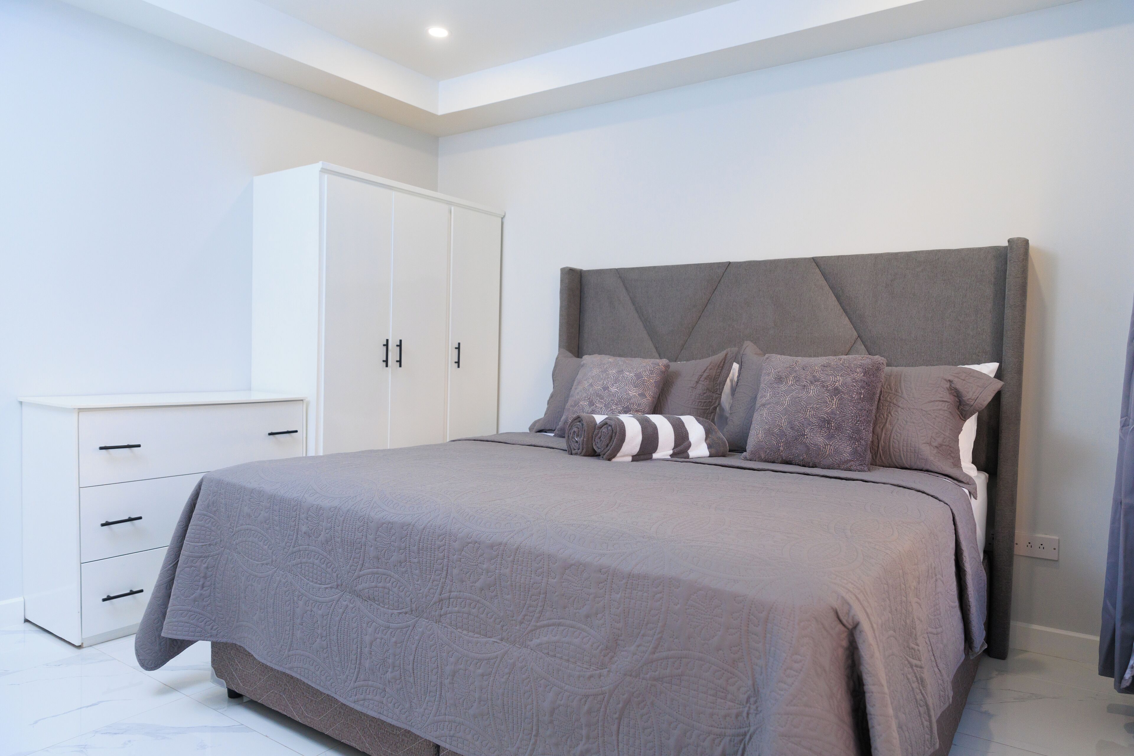 Un dormitorio con una cama grande, un armario y una lámpara en el techo.
