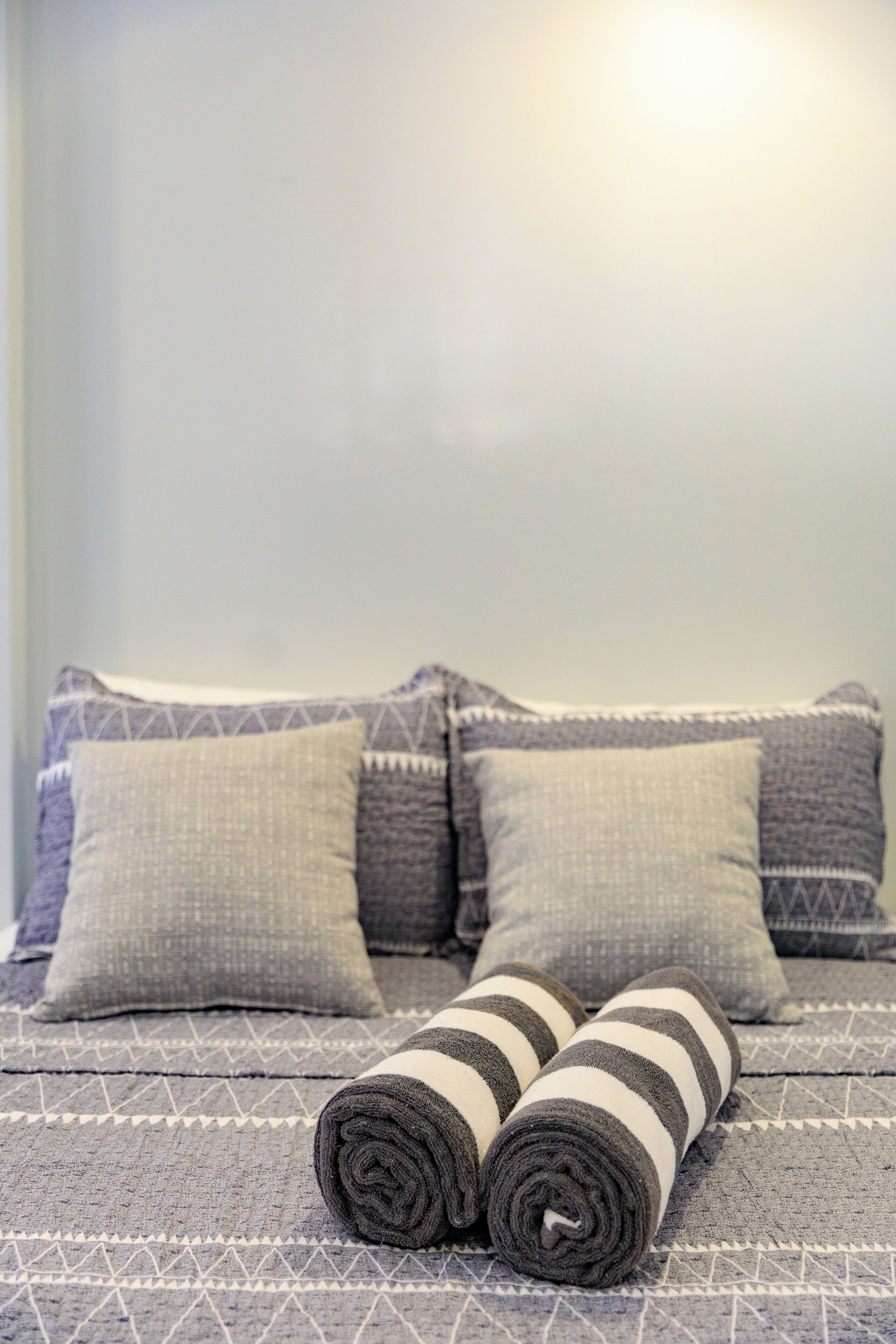 Un lit avec une couvre-lit à motifs et des oreillers, ainsi que deux serviettes enroulées posées sur le lit.