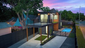A modern two-story house with a balcony, a swimming pool, and a well-maintained garden. - Brand New Austin Downtown Home -Pool (Austin)