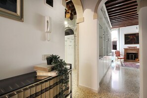 Un pasillo con un teléfono, libros y una planta sobre una estantería.