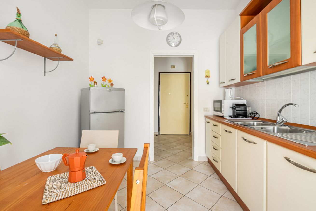 A compact kitchen with a refrigerator, a coffee machine, and a sink.