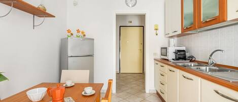 A compact kitchen with a refrigerator, a coffee machine, and a sink.