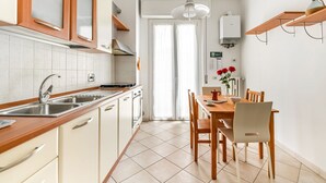 A modern kitchen with a dining area, featuring a sink, stove, cabinets, and a dining table with chairs. - GuestHost - Cozy apartment of about 60 sqm, for up to 4 people, located on the second floor of a building with a lift (some steps to access). The apartment is located in a quiet residential area, less than 10 minutes on foot from the Cascine Park, and we (Firenze)