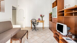 A living room with a sofa, a wooden desk, a television, and a bookshelf. - GuestHost - Cozy apartment of about 60 sqm, for up to 4 people, located on the second floor of a building with a lift (some steps to access). The apartment is located in a quiet residential area, less than 10 minutes on foot from the Cascine Park, and we (Firenze)