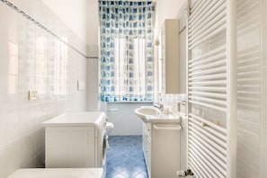 Un baño estrecho con lavadora, lavabo e inodoro.