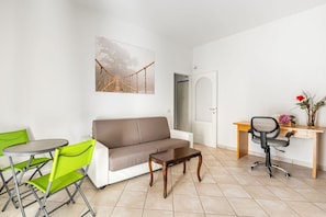 Una sala de estar con un sofá, una mesa de centro, un escritorio con una silla y una mesa de comedor con sillas.