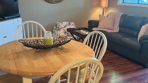 A dining area with a wooden table and chairs, a decorative mirror, a television, and a window with blinds. - 1 BR Condo Next to Pool with a View, 1 Mile to SDC. 3 Miles to Branson’s Strip.  (Reeds Spring)