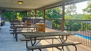 A covered picnic area with benches and tables, a pool in the background, and a fenced area. - 1 BR Condo Next to Pool with a View, 1 Mile to SDC. 3 Miles to Branson’s Strip.  (Reeds Spring)