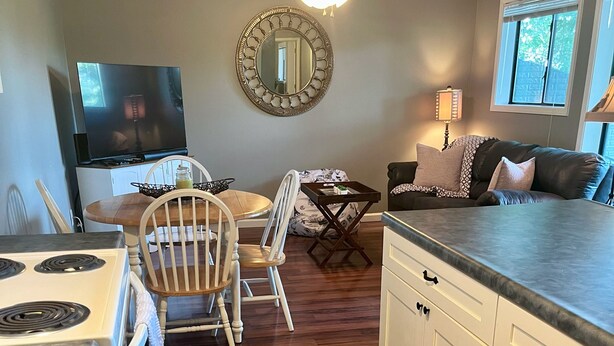 A kitchen with a stove, white cabinets, a wooden dining table with chairs, a ceiling fan, and a window with blinds. - 1 BR Condo Next to Pool with a View, 1 Mile to SDC. 3 Miles to Branson’s Strip.  (Reeds Spring)