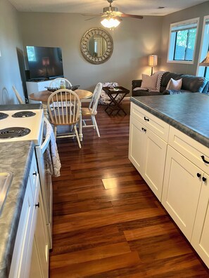 A kitchen with a stove, white cabinets, a wooden dining table with chairs, a ceiling fan, and a window with blinds. - 1 BR Condo Next to Pool with a View, 1 Mile to SDC. 3 Miles to Branson’s Strip.  (Reeds Spring)