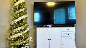 A room with a Christmas tree, a flat-screen TV, and a white cabinet. - 1 BR Condo Next to Pool with a View, 1 Mile to SDC. 3 Miles to Branson’s Strip.  (Reeds Spring)