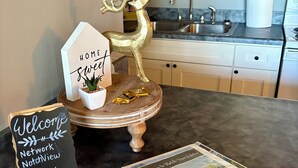 A kitchen with a dark countertop, a decorative golden reindeer, a welcome sign, and a framed welcome card. - 1 BR Condo Next to Pool with a View, 1 Mile to SDC. 3 Miles to Branson’s Strip.  (Reeds Spring)