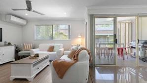 Un salon moderne avec un canapé, une table basse et une porte vitrée donnant sur un espace extérieur.
