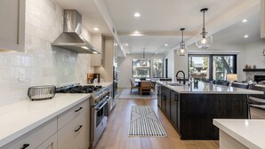 A modern kitchen with white cabinetry, a central island, and pendant lighting.
