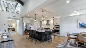 A spacious kitchen with a central island, modern appliances, and a dining area with chairs.