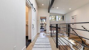A modern interior with a staircase, wooden flooring, and a view to the outside.