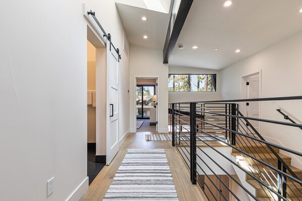 Un interior moderno con una escalera, suelo de madera y vistas al exterior.