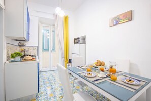 Una cocina moderna con comedor, que incluye un desayuno con cruasanes, zumo de naranja y un bol de fruta.