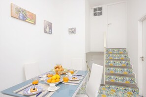 Una mesa de comedor con productos para el desayuno, una escalera con baldosas florales y una puerta blanca.