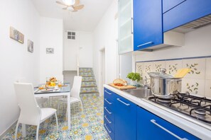 Una cocina con gabinetes azules, estufa a gas y piso de baldosas.