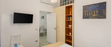 A bedroom with a bed, a TV, a wardrobe, and a painting.