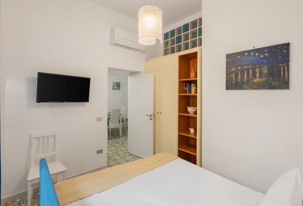Une chambre à coucher avec un lit, une télévision, une armoire et un tableau.