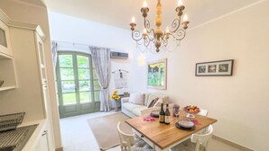 A modern kitchen with white cabinets, a dining table with chairs, a chandelier, and a view of the outdoors through a glass door. - Langhe Nascetta, authentic atmosphere (Novello)