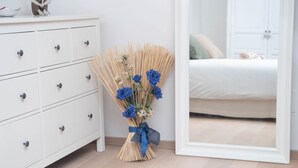 A bedroom with a white dresser, a mirror, and a bouquet of blue flowers. - Langhe Nascetta, authentic atmosphere (Novello)