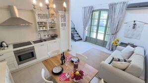 A modern kitchen with white cabinetry, a built-in oven, and a dining area with a wooden table set for two. - Langhe Nascetta, authentic atmosphere (Novello)