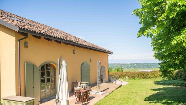 A house with a tiled roof, a patio with a table and chairs, and a well-maintained lawn. - Langhe Nascetta, authentic atmosphere (Novello)
