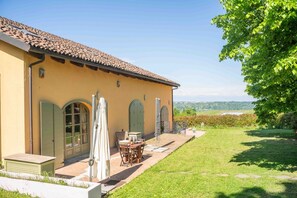 A house with a tiled roof, a patio with a table and chairs, and a well-maintained lawn. - Langhe Nascetta, authentic atmosphere (Novello)