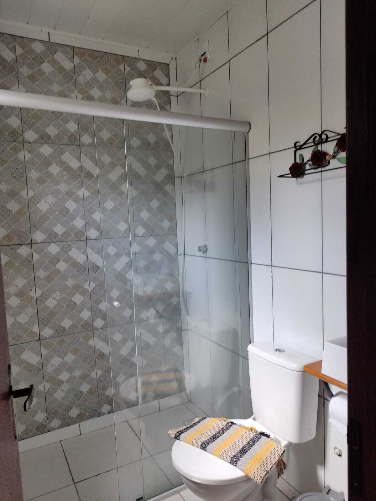 A bathroom with a shower enclosure, a toilet, and a sink.