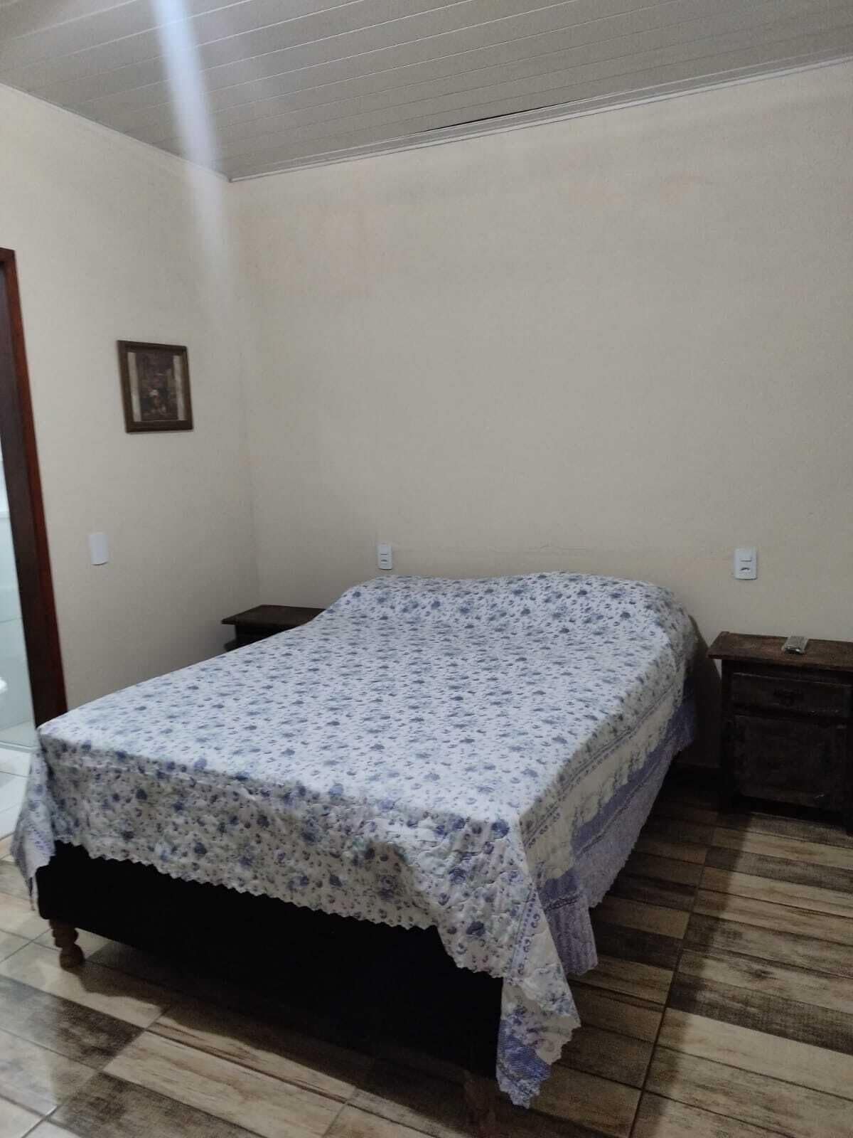 Un dormitorio con una cama cubierta por una colcha estampada, una mesita de noche de madera y una pequeña mesa.