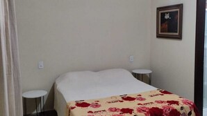 Um quarto com uma cama, uma pequena mesa redonda e um quadro na parede.