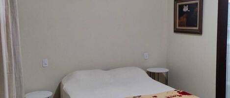 Un dormitorio con una cama, una mesita redonda y un cuadro en la pared.