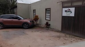 Um SUV vermelho estacionado em frente a um edifício com uma placa que diz 'Pensionhaus'.