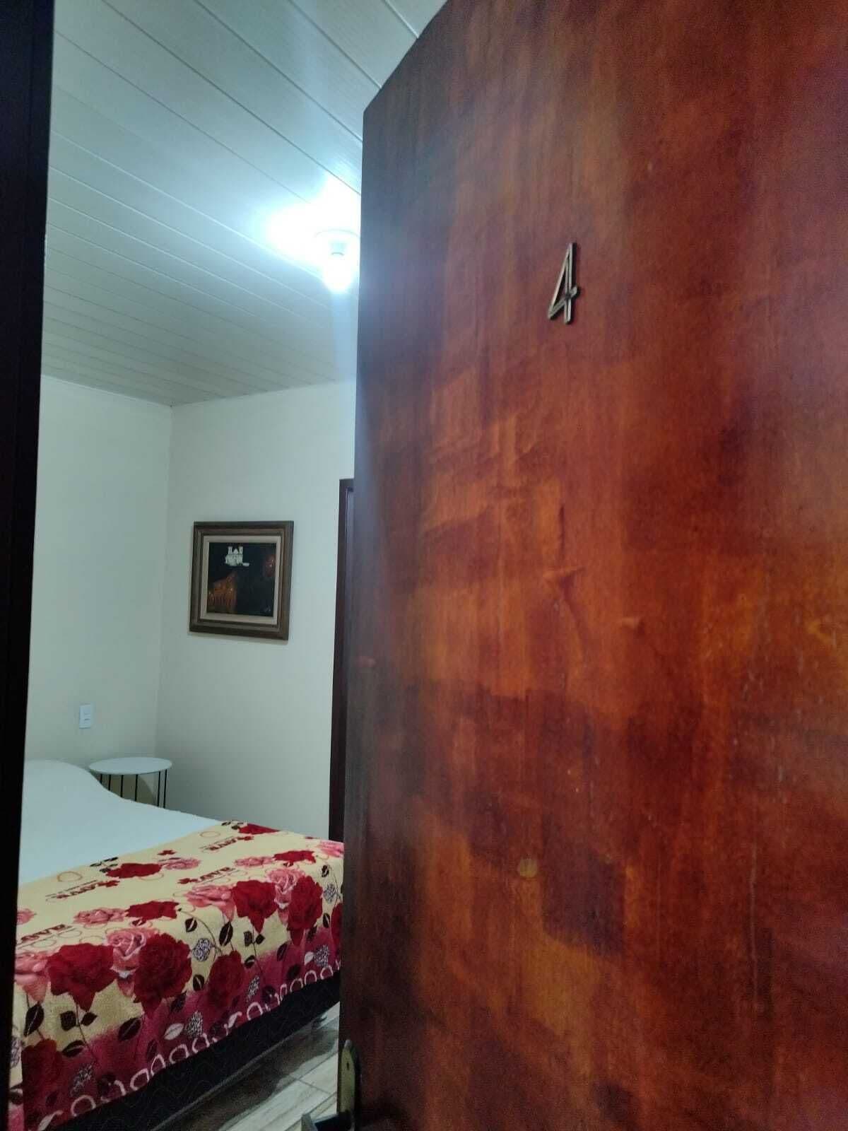 Una habitación con una cama, una mesita pequeña y un cuadro colgado en la pared.
