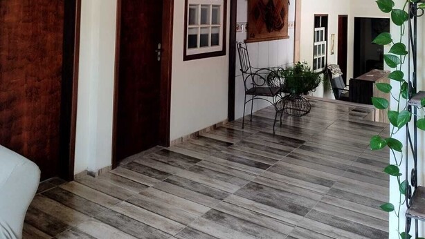Quarto espaçoso com piso de madeira, área de jantar com mesa e cadeiras, e uma grande janela com vista para o exterior.