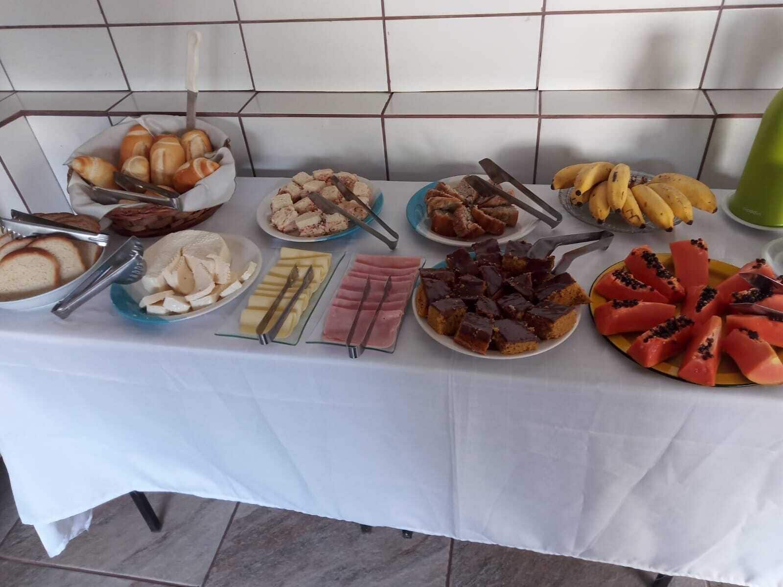 Une table de buffet proposant divers aliments, notamment du pain, du fromage, du jambon, du chocolat et des fruits.