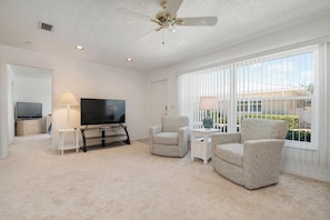 Relax in this inviting living room with a flat-screen TV, armchairs, and a side table.