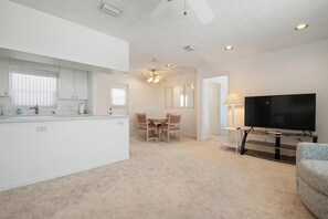 Cozy living space with a dining area, flat-screen TV, and ceiling fan.