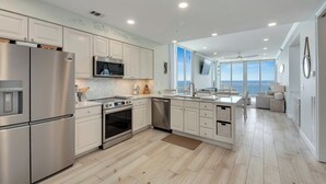 A modern kitchen with stainless steel appliances, white cabinetry, and a large island. - Penthouse Paradise at The Pearl! (Navarre Beach)